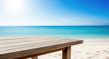 Fototapeta premium A weathered wooden table stands on soft white sand, overlooking the calm blue ocean during a bright, sunny day with clear turquoise water, plank, ocean, copy space
