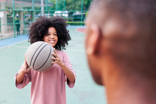 Girl with basketball faces another player on court