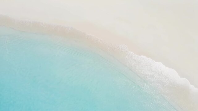 Aerial view of turquoise ocean waves gently meeting white sandy beach under soft sunlight
