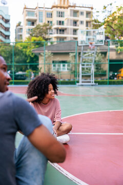 Friends chatting on a basketball court in the city.