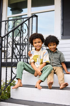 Two Kids Sit Together on Home Steps
