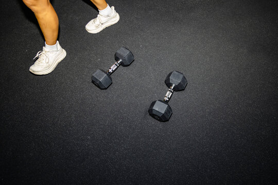 Gym floor detail with dumbbells and athlete