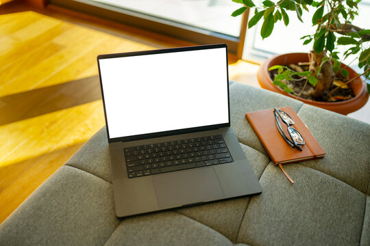 A laptop sits on a gray table near a window