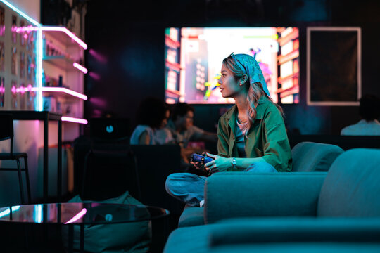 Woman gaming in a neon-lit arcade lounge.