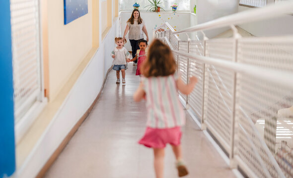 Children running in school hallway with teacher