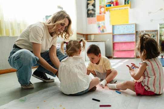 Educator guiding children creating art in early learning classroom