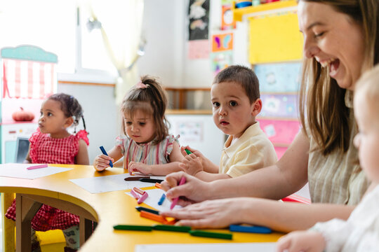 Children learning and drawing with teacher in early