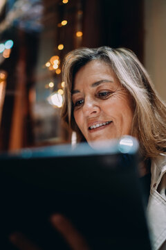 Close up portrait smiling mature woman using tablet computer. Happy female looking at screen, checking social media notification, online banking payment, digital lifestyle, authentic representation