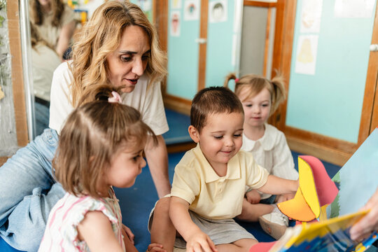 Preschool teacher reading pop up storybook to young children