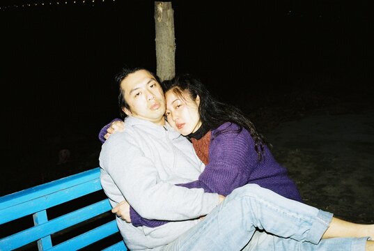 Young Couple Embracing on Park Bench at Night
