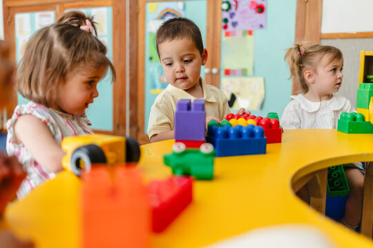 Toddlers playing colorful building blocks on yellow table
