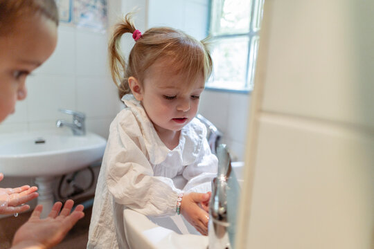 Young child washing hands in bathroom learning hygiene