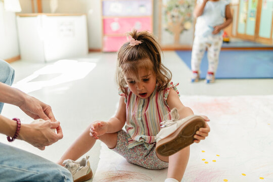 Young girl learning tying shoe laces assistance