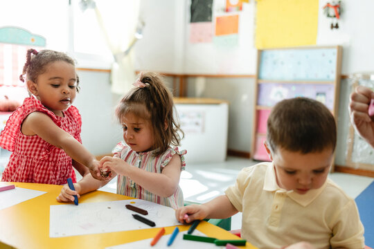 Preschool children learning and drawing with crayons