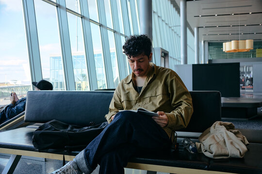 Traveler reading in airport seating area by windows