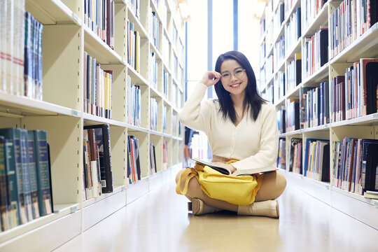 Young student reading in library aisle