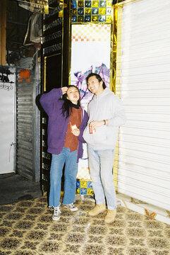 Grinning Young Couple Posing in Doorway at Night