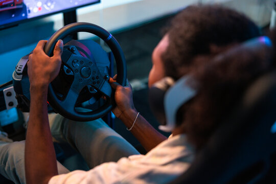 Man using a racing wheel in a simulator setup.