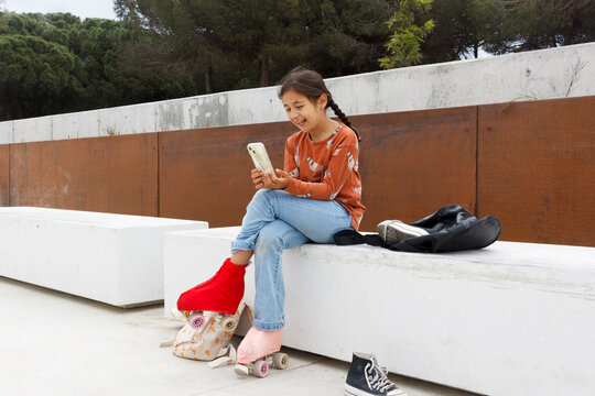 Girl Uses Phone While Sitting on a Bench 
