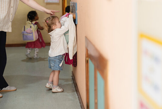 Child learning independence by hanging clothes in kindergarten