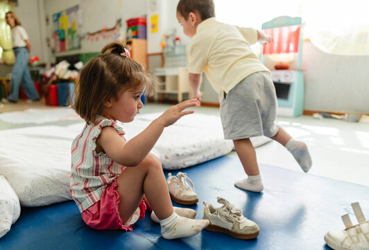 Toddler girl learning self dressing in kindergarten classroom