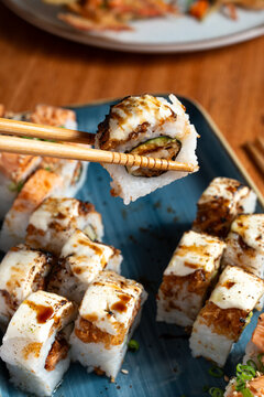  holding sushi roll with chopsticks