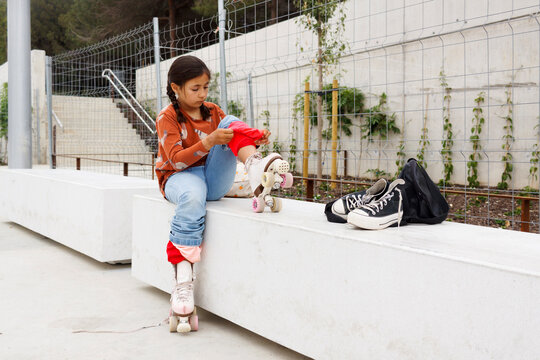 Girl Puts on Roller Skates at a Park 