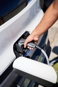 Person plugging electric vehicle for charging at home