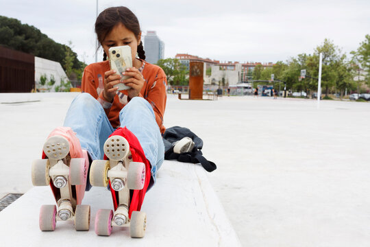 Girl Sits on a Bench With Skates While Using a Phone
