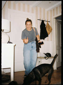 Woman laughing with dog in home hallway