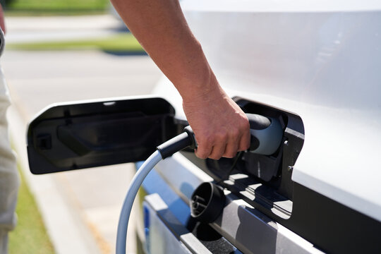 Man plugging power cable into electric car for charging