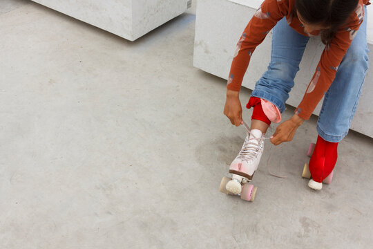 Girl Putting on Roller Skates in a Skate Park 
