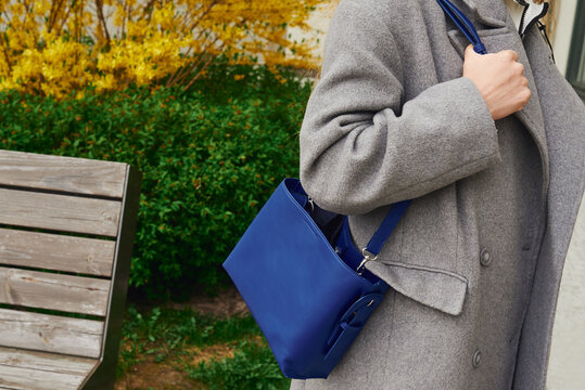 Woman carries a blue bag while standing outdoors