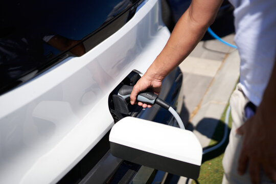 Person charging electric vehicle at home station