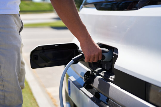 Man connecting charging cable to electric vehicle