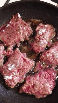 Slices of beef liver fry in a hot cast iron skillet with bubbling oil and flour coating. Concept of home cooking, protein rich nutrition, and traditional culinary preparation.