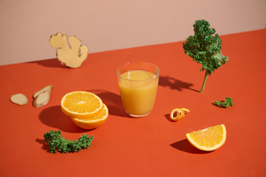 Freshly squeezed orange juice with ingredients on orange background