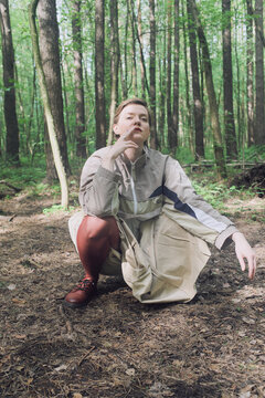 Person sitting in forest with green trees and brown ground