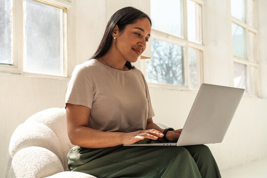 Smiling Professional Working on Laptop in Bright Studio