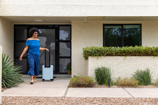 Black woman luggage leave home door 