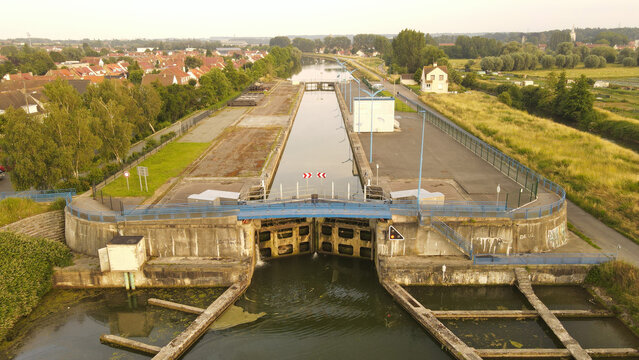 Aerial view of the canal lock system in Saint-Omer surrounded by green fields and residential buildings in Saint-Omer, Hauts-de-France, France.