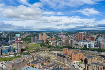 Obraz premium Aerial view of Leeds city centre showing South Bank regeneration railway lines modern residential towers commercial buildings and ongoing construction beneath a dramatic blue sky on a summer day