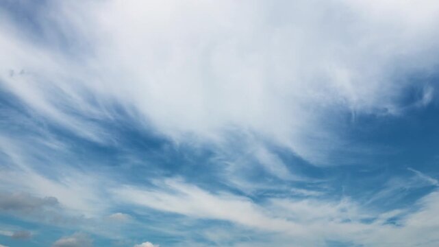 Time lapse of beautiful white wispy clouds moving across a bright blue sky..