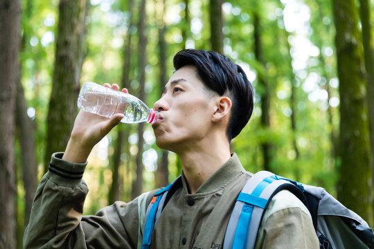 Young hiker drinking water in forest during outdoor adventure