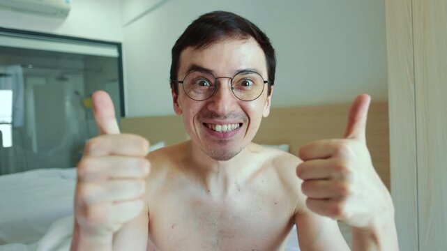 Energetic caucasian man with eyeglasses smiling widely while making a double thumbs up gesture. His overexcited and pleased expression conveys strong approval, success, and satisfaction