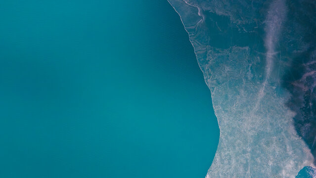 Aerial view of Attabad Lake showing the contrast between the deep turquoise water and the icy, frozen shoreline in Hunza Nagar, Gilgit, Pakistan.