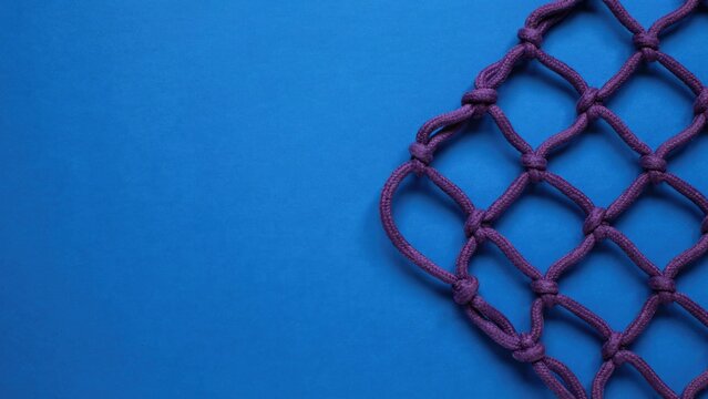 Purple knotted rope netting on a solid blue background