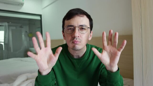 Funny and slightly crazy man dancing and making goofy hand gestures in front of the camera. Cheerful eccentric guy in glasses joyfully grooving, wagging index fingers and waving palms