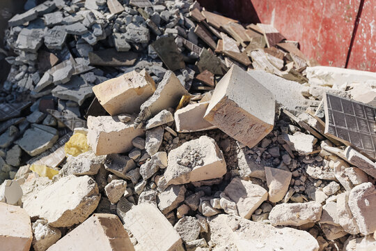 Construction rubble and demolition waste piled in container. Broken concrete blocks and debris from building renovation. Industrial recycling background showing construction materials disposal.