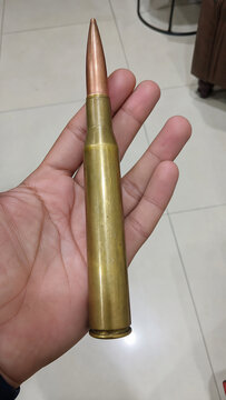 Person holding a large caliber rifle bullet in hand